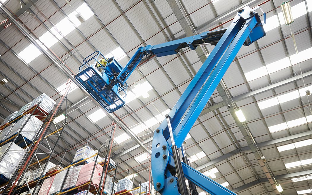Moving stock in a warehouse with a cherry picker, low angle 1050x656