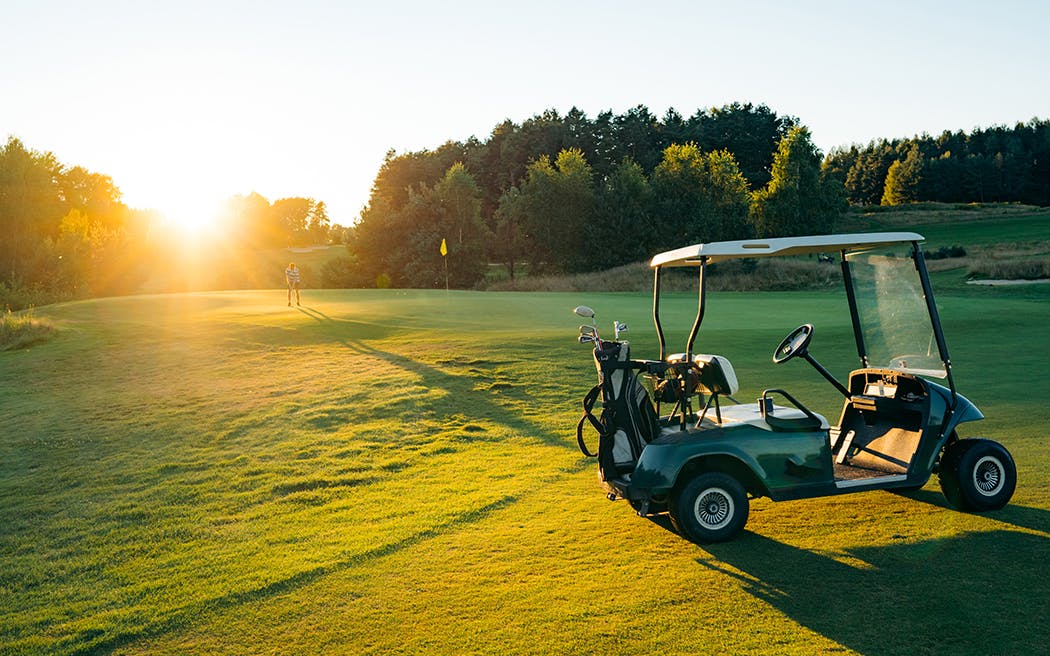 Golf cart or golf club cars in a beautiful golf course. Green golf and light of sun to beauty view for player to happy 1050x656