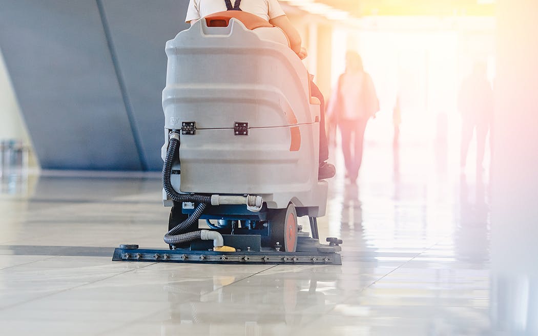 Close-up sweeper machine cleaning. Concept clean airport from debris 1050x656